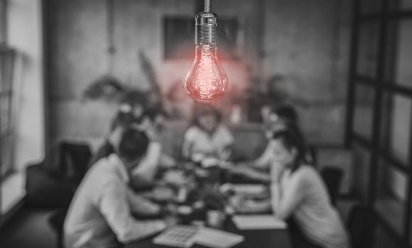 Groupe de personnes qui travaillent à table avec une ampoule au dessus de leur tête